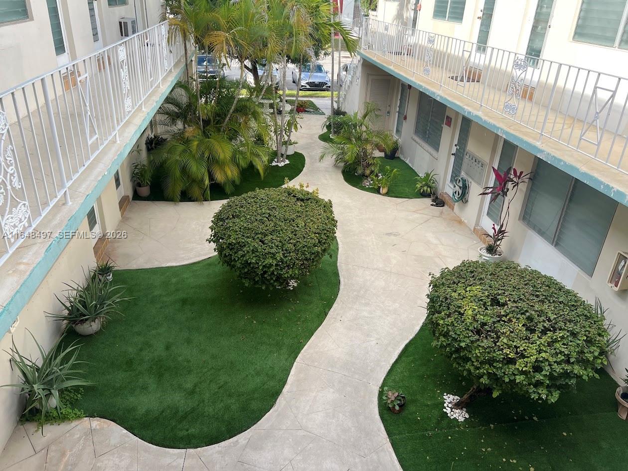 An elevated view of a courtyard featuring artificial turf, landscaping, and concrete walkways between buildings — 2072 NE 169th St # 12, North Miami Beach FL 33162, NORTH MIAMI BEACH, FL