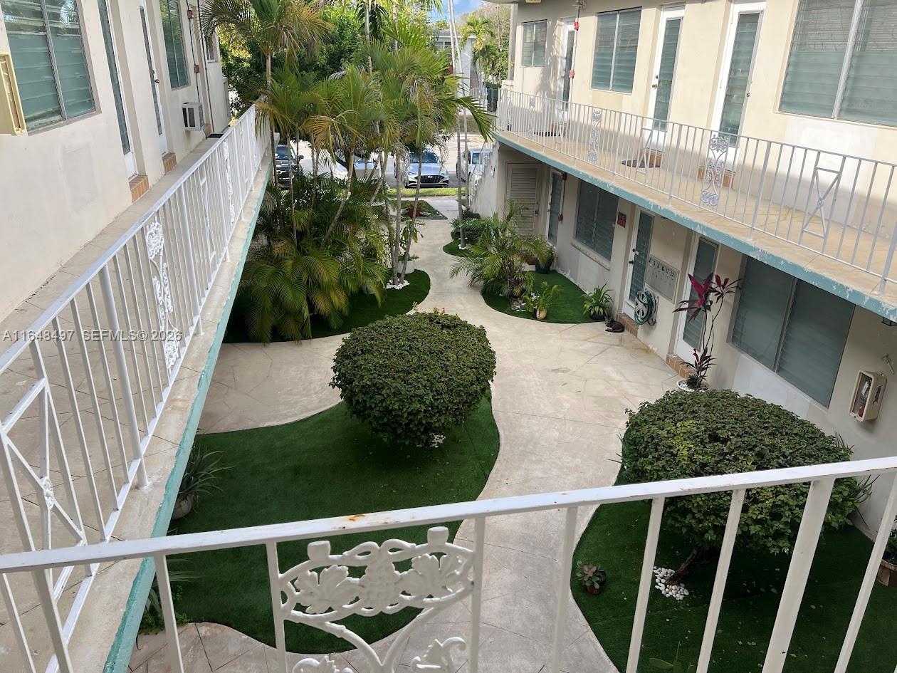 An elevated view of a courtyard between two apartment buildings with walkways and landscaping — 2072 NE 169th St # 12, North Miami Beach FL 33162, NORTH MIAMI BEACH, FL