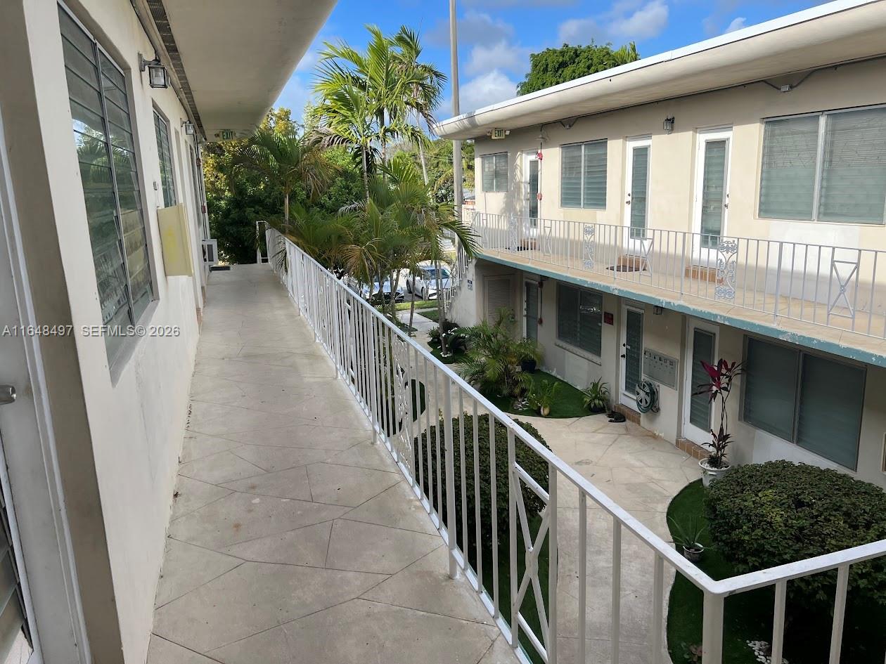 An exterior walkway with white railings overlooks a courtyard between two levels of apartment units — 2072 NE 169th St # 12, North Miami Beach FL 33162, NORTH MIAMI BEACH, FL