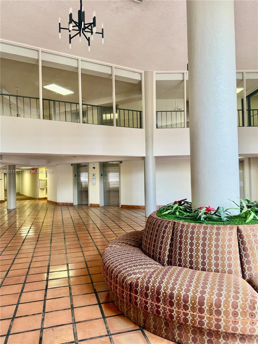 A lobby features a curved patterned sofa, a central pillar, tile flooring, and two elevators — 5700 SW 127th Ave # 1413, Miami FL 33183, MIAMI, FL