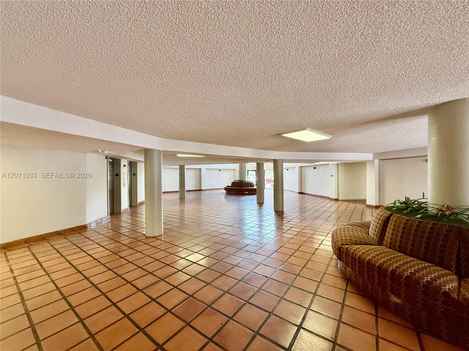 A spacious lobby features a tiled floor, support columns, and a curved patterned sofa — 5700 SW 127th Ave # 1413, Miami FL 33183, MIAMI, FL