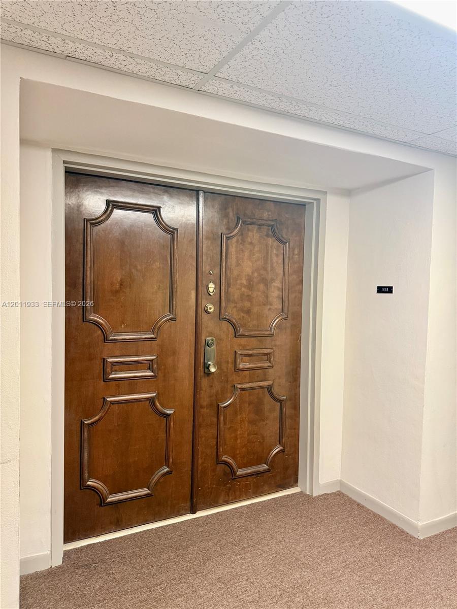 A pair of dark wood double doors with decorative panels sits in a carpeted hallway — 5700 SW 127th Ave # 1413, Miami FL 33183, MIAMI, FL