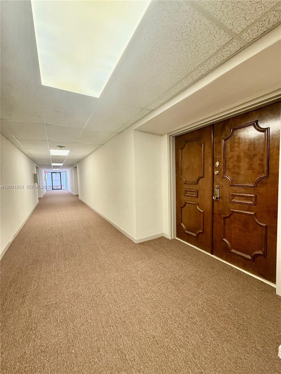 A long, carpeted hallway features a drop ceiling and a set of double wooden doors — 5700 SW 127th Ave # 1413, Miami FL 33183, MIAMI, FL