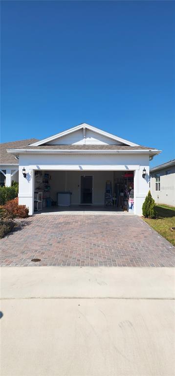A view of a residential garage exterior with a brick paver driveway — 1823 SPRING SHOWER CIR, KISSIMMEE, FL