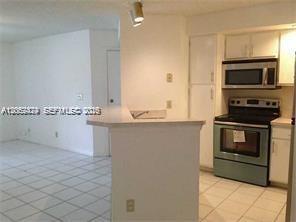 A kitchen with white cabinets and appliances overlooks a tiled living area — 3380 N Pinewalk Dr N # 1116, Margate FL 33063, MARGATE, FL