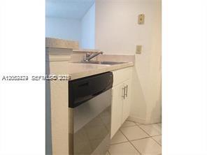 A kitchen features a stainless steel dishwasher, white cabinets, and light-colored tile flooring — 3380 N Pinewalk Dr N # 1116, Margate FL 33063, MARGATE, FL