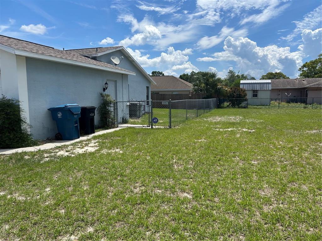 A view of a backyard with a chain-link fence, a shed, and two trash cans — 5482 MARINER BOULEVARD, SPRING HILL, FL