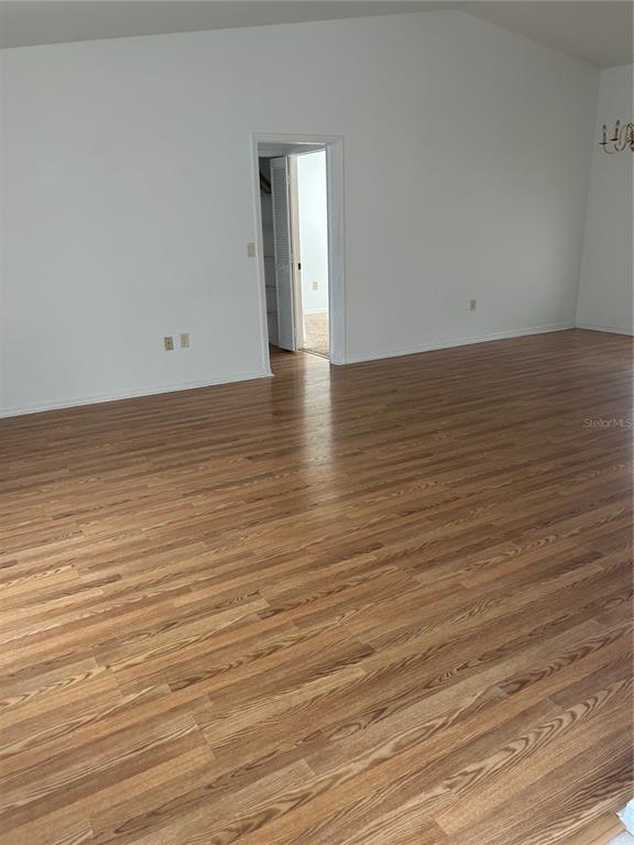 An empty room with light wood-look flooring, white walls, and a doorway leading to a closet — 5482 MARINER BOULEVARD, SPRING HILL, FL