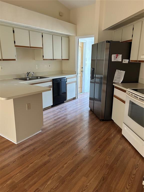 A kitchen features light-colored cabinets, a stainless steel refrigerator, a black dishwasher, and wood-look flooring — 5482 MARINER BOULEVARD, SPRING HILL, FL