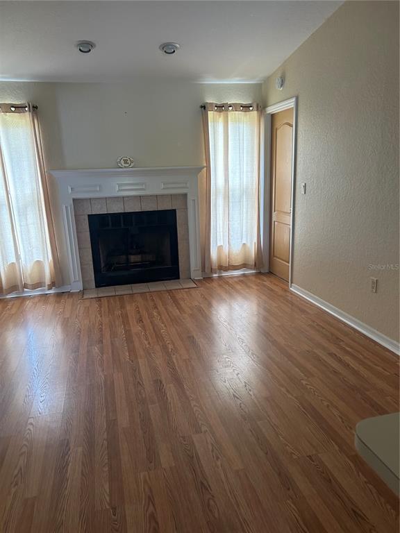 A living room features a fireplace with a white mantel, wood flooring, and two windows — 5482 MARINER BOULEVARD, SPRING HILL, FL
