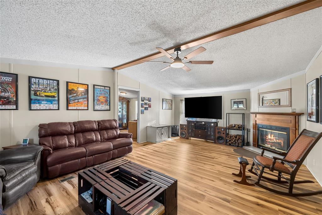 A living room features a brown leather sofa, a fireplace, a ceiling fan, and wood flooring — 360 SE 30TH AVENUE, TRENTON, FL