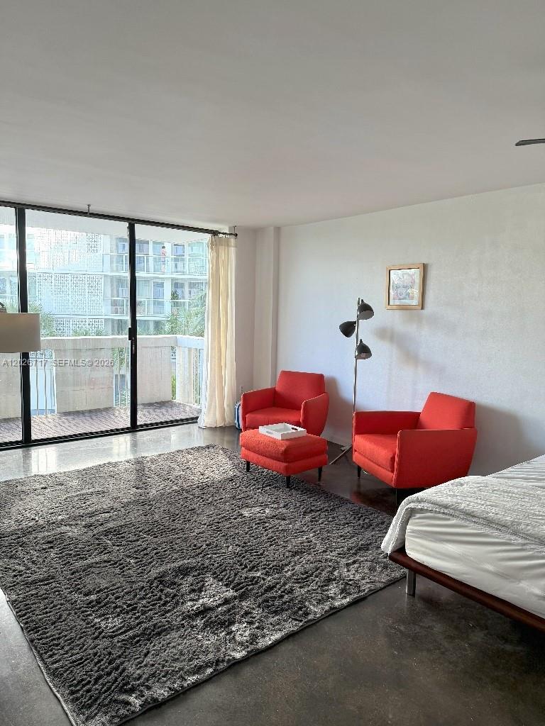 A bedroom features concrete floors, two red armchairs with an ottoman, and a sliding glass door — 800 West Ave # 342, Miami Beach FL 33139, MIAMI BEACH, FL