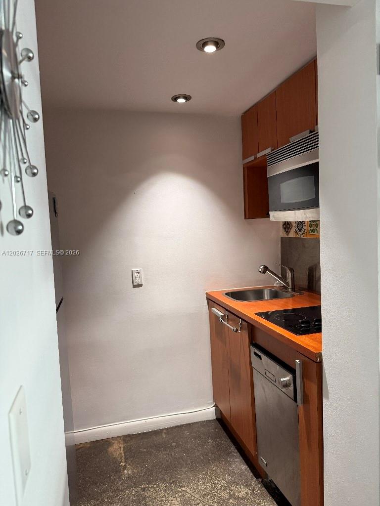 A small kitchenette features wood cabinets, a stainless steel dishwasher, and a sink — 800 West Ave # 342, Miami Beach FL 33139, MIAMI BEACH, FL