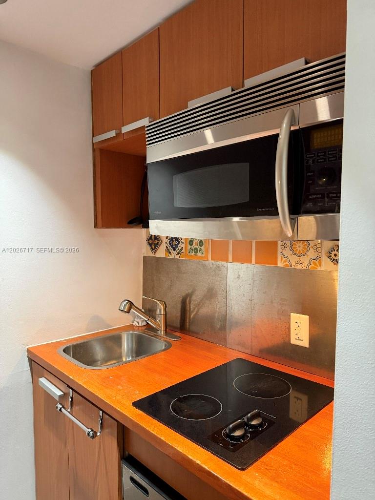 A small kitchen features wood countertops, a stainless steel sink, a cooktop, and upper cabinets — 800 West Ave # 342, Miami Beach FL 33139, MIAMI BEACH, FL