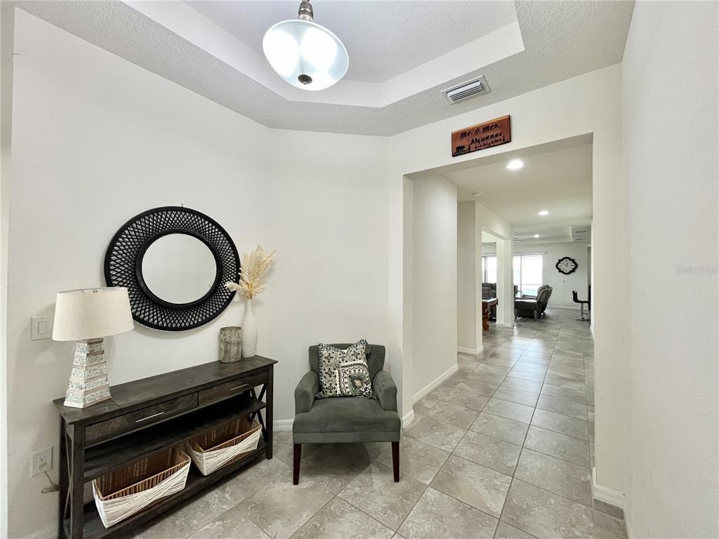 A tiled entryway features a console table, an armchair, and a doorway leading to a living area — 4710 SW 65TH PLACE, OCALA, FL