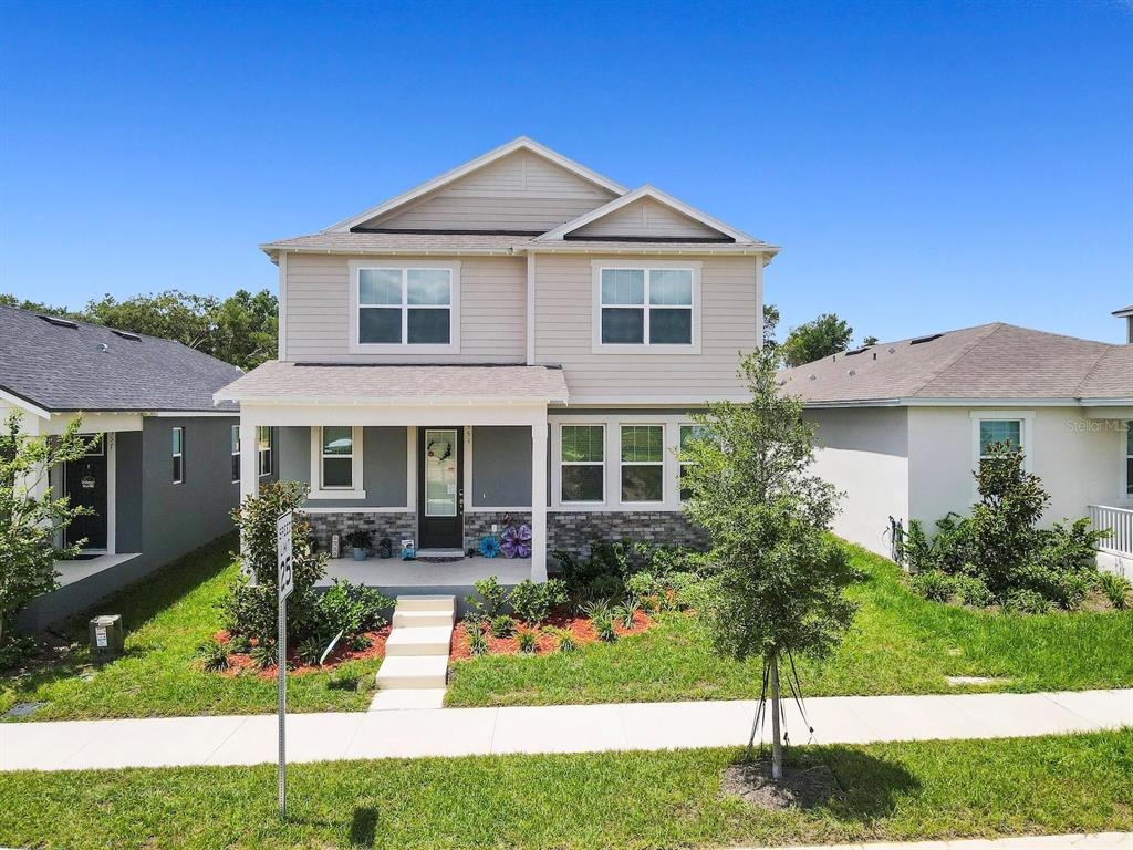 A two-story house with a front porch, gray siding, and a stone-accented lower exterior — 353 FREE RANGE DRIVE, GROVELAND, FL