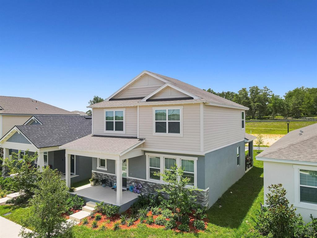 A two-story house with beige siding, a gray stucco lower level, and a front porch — 353 FREE RANGE DRIVE, GROVELAND, FL