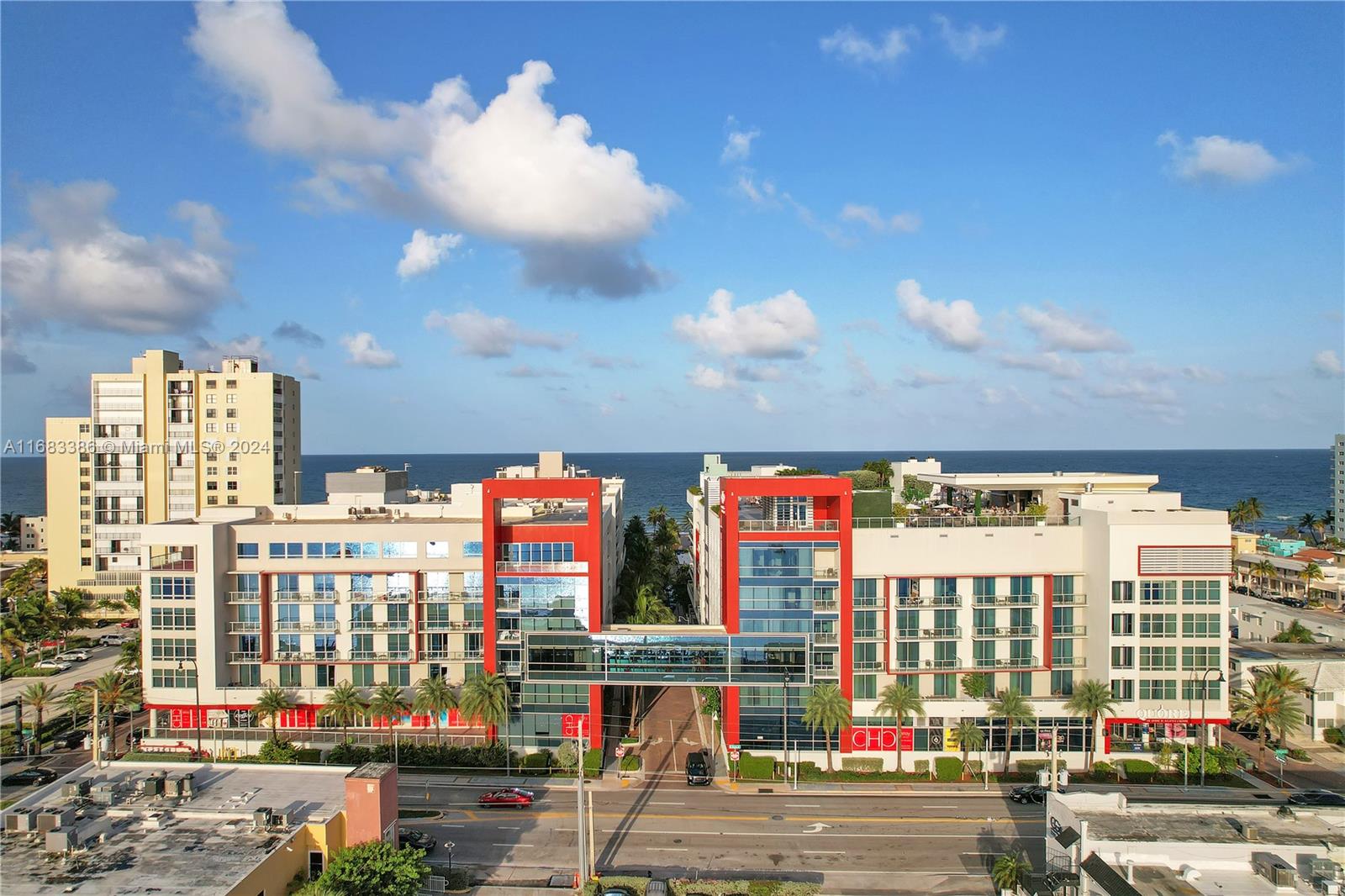 An aerial view shows two modern, connected buildings with red accents facing the ocean — 777 N Ocean Dr # S316, Hollywood FL 33019, HOLLYWOOD, FL