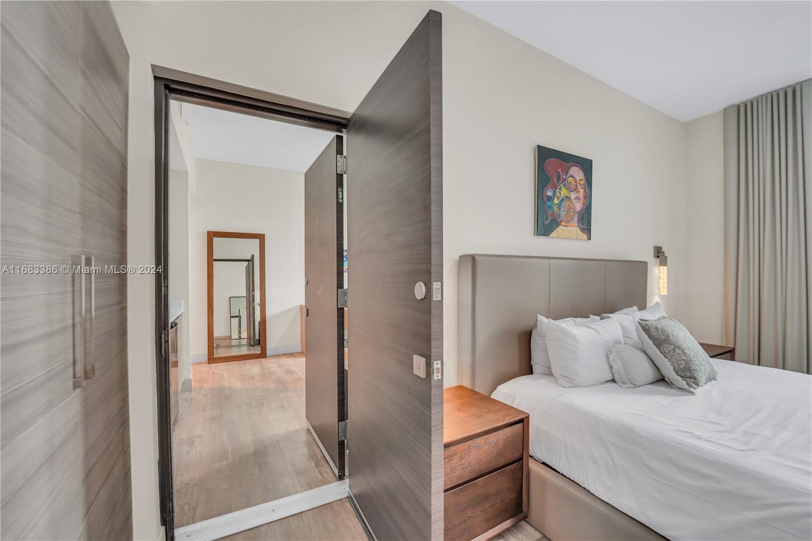 A bedroom features a wood-paneled door, a bed with a leather headboard, and a mirror — 777 N Ocean Dr # S316, Hollywood FL 33019, HOLLYWOOD, FL