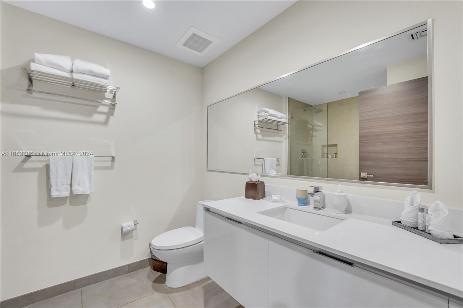 A modern bathroom features a white vanity, a large mirror, and a wall-mounted towel rack — 777 N Ocean Dr # S316, Hollywood FL 33019, HOLLYWOOD, FL