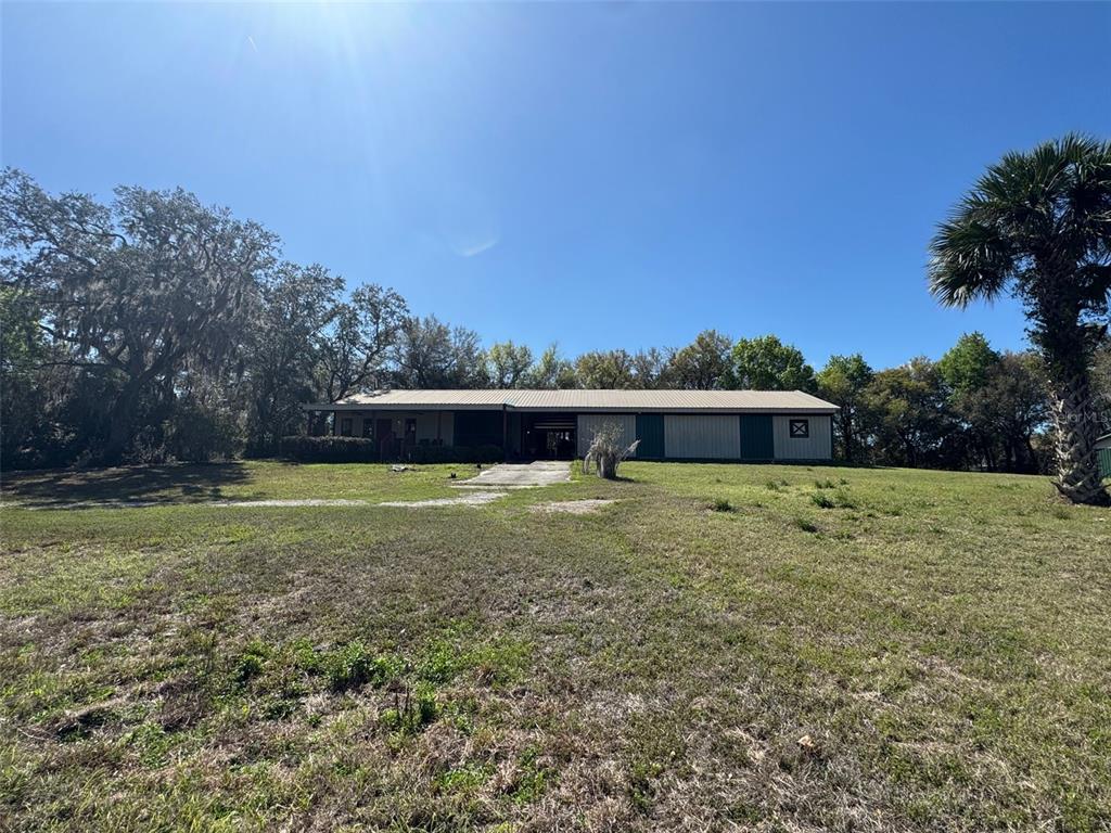 A wide, single-story metal building with a covered porch sits on a grassy lot — 1065 S MASSACHUSETTS AVENUE, DELAND, FL