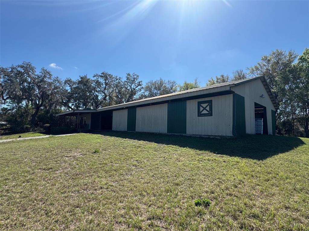 A large metal barn with a covered porch sits on a grassy lot — 1065 S MASSACHUSETTS AVENUE, DELAND, FL