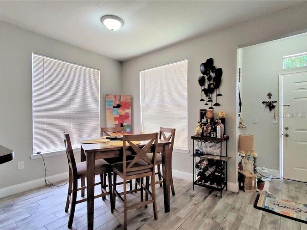A dining area features a wooden table, four chairs, a bar cart, and light-colored flooring — 6025 WESTGATE DRIVE UNIT 2511, ORLANDO, FL
