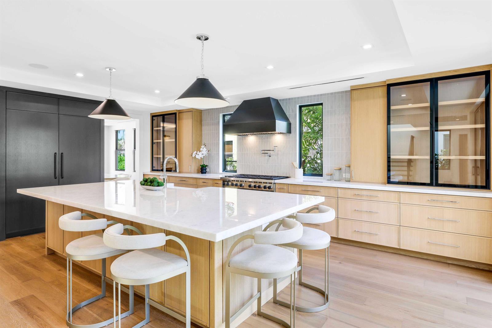 A modern kitchen features a large white island, light wood cabinetry, and black metal accents — 317 Greymon Drive, West Palm Beach FL 33405, WEST PALM BEACH, FL