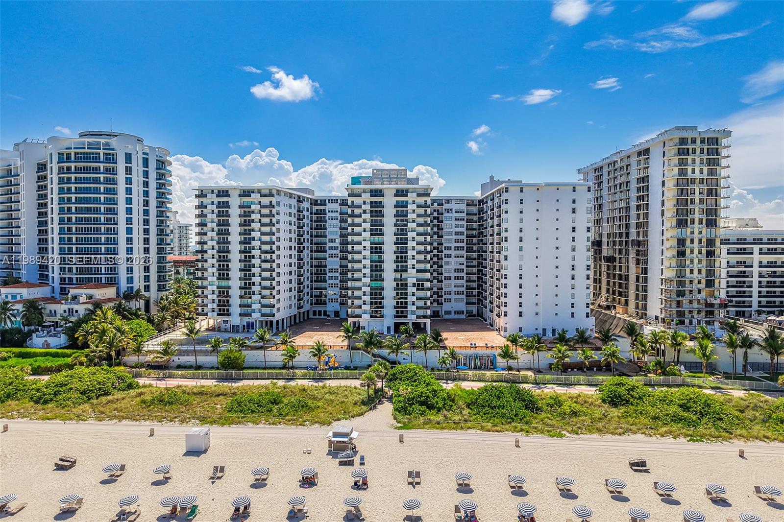 An aerial view of a multi-story beachfront apartment complex with a sandy beach in front — 6039 Collins Ave # 833, Miami Beach FL 33140, MIAMI BEACH, FL