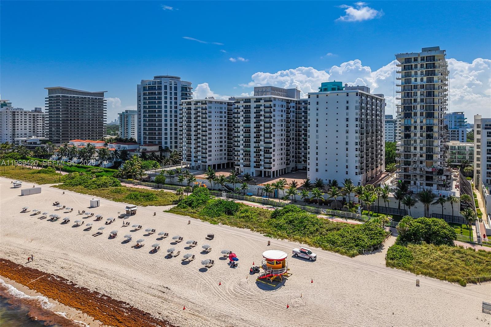 An aerial view shows a sandy beach with a lifeguard tower and several high-rise buildings — 6039 Collins Ave # 833, Miami Beach FL 33140, MIAMI BEACH, FL