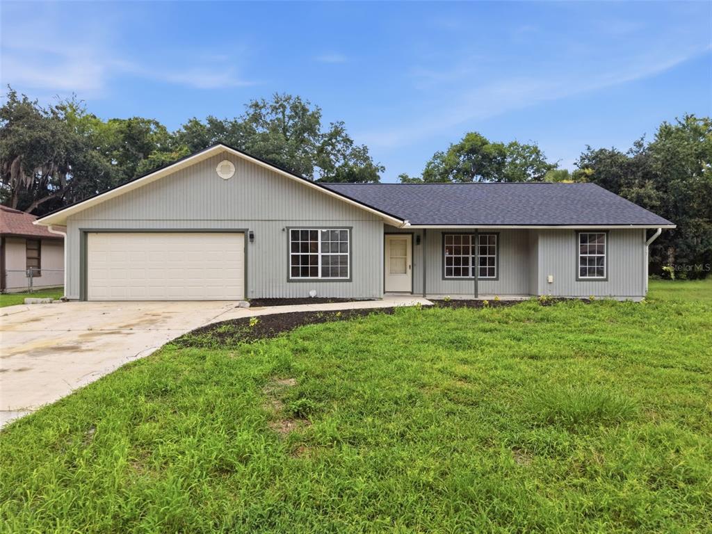 A single-story house with gray vertical siding, a two-car garage, and a dark shingled roof — 2509 JUNIPER DRIVE, EDGEWATER, FL