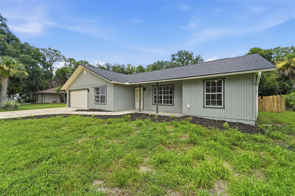 A single-story house with gray vertical siding, a dark shingled roof, and a front garage — 2509 JUNIPER DRIVE, EDGEWATER, FL