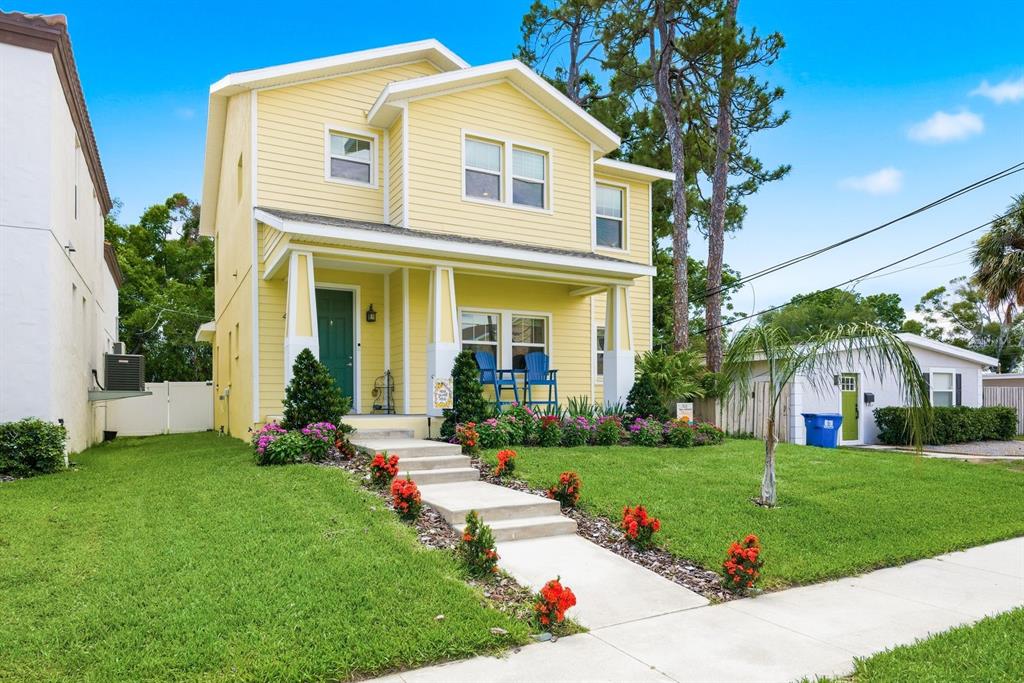 A two-story yellow house with a front porch, concrete walkway, and landscaped lawn — 4920 3RD STREET N, ST PETERSBURG, FL