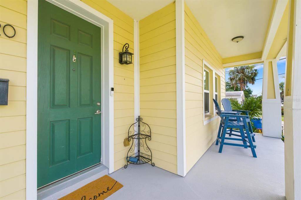 A yellow house exterior features a green front door, a porch, and blue chairs — 4920 3RD STREET N, ST PETERSBURG, FL