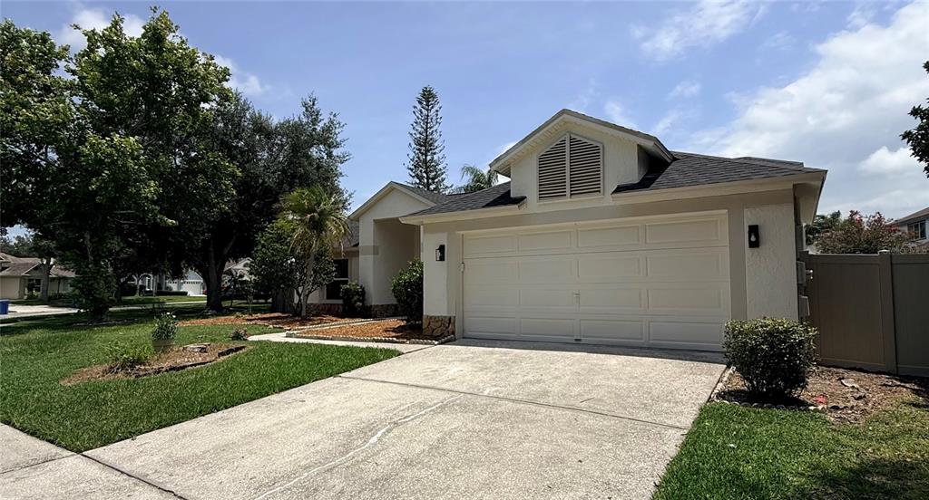 A single-story house with a white garage, tan stucco exterior, and a concrete driveway — 9207 MILL CIRCLE, TAMPA, FL