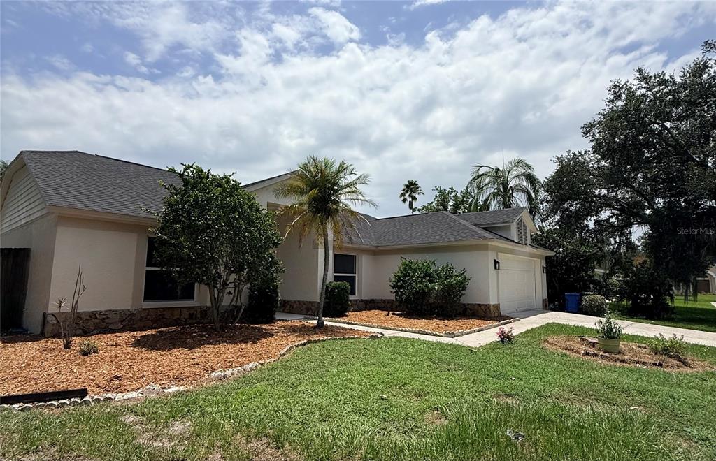 A single-story house with a beige exterior, stone accents, and a palm tree in front — 9207 MILL CIRCLE, TAMPA, FL