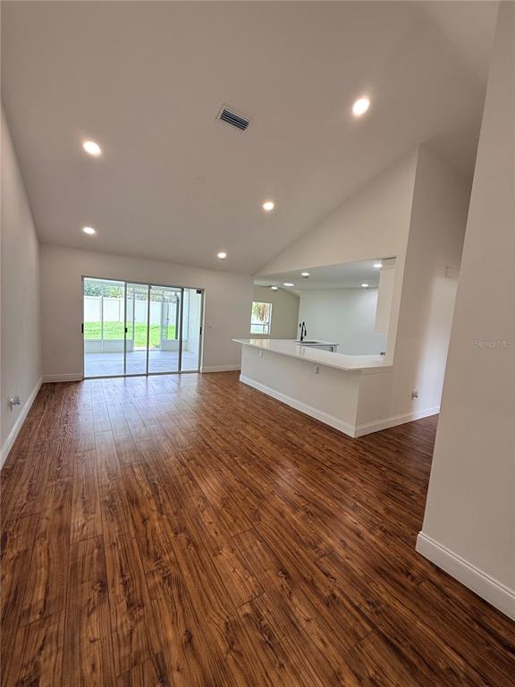 An open-concept living area features wood-look flooring, recessed lighting, and a kitchen breakfast bar — 9207 MILL CIRCLE, TAMPA, FL