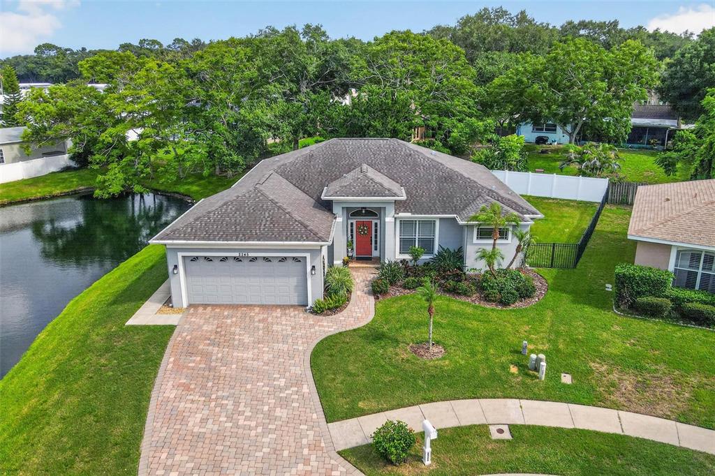 An aerial view of a single-story house with a gray roof, red door, and paver driveway — 2245 MISTY COURT, DUNEDIN, FL