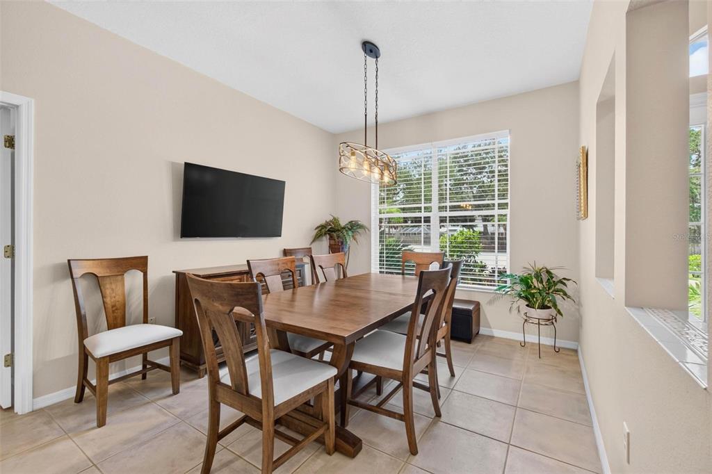 A dining room with a wooden table, six chairs, a sideboard, and a hanging light fixture — 2245 MISTY COURT, DUNEDIN, FL
