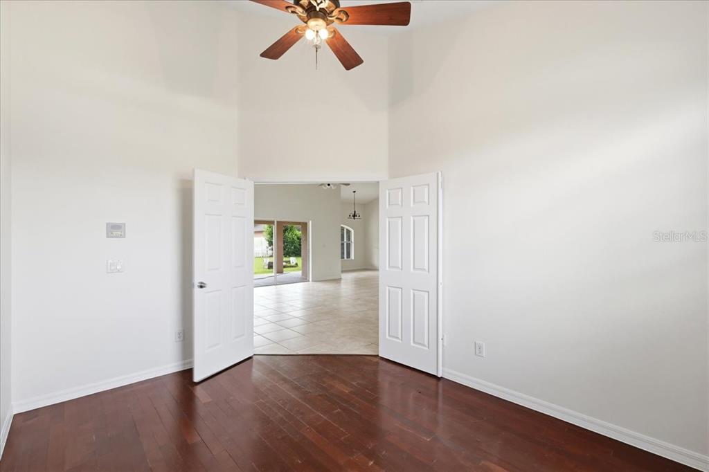 A room with dark wood floors and double doors opening into a tiled living area — 4303 SHOSHONE COURT, ST CLOUD, FL