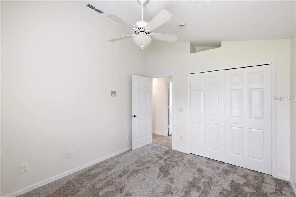 A bedroom with white walls, gray carpet, a ceiling fan, and a white closet — 4303 SHOSHONE COURT, ST CLOUD, FL