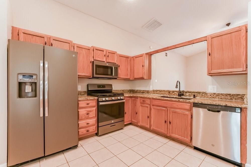 A kitchen with wood cabinets, stainless steel appliances, and tiled flooring — 4166 SHADOW CREEK CIRCLE, OVIEDO, FL