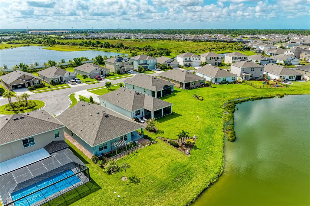 An aerial view shows suburban houses with swimming pools and backyards bordering a large pond — 12509 NIGHT VIEW DRIVE, SARASOTA, FL