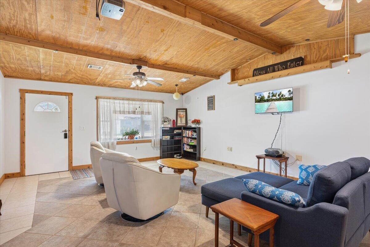 A living room features a vaulted wood-paneled ceiling, tile flooring, and a blue sectional sofa — 1735 40th Avenue, Vero Beach FL 32960, VERO BEACH, FL