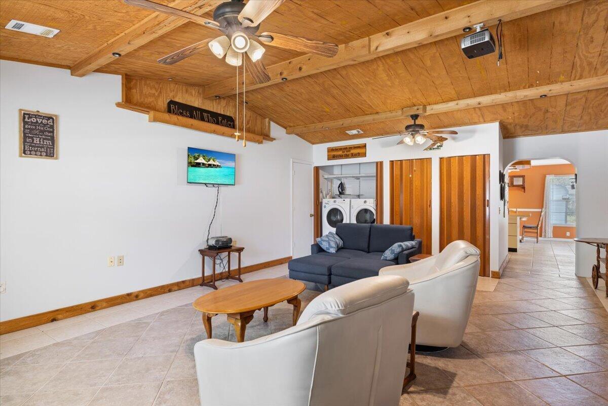 A living room with tile floors, a wood-paneled ceiling, and a laundry area — 1735 40th Avenue, Vero Beach FL 32960, VERO BEACH, FL