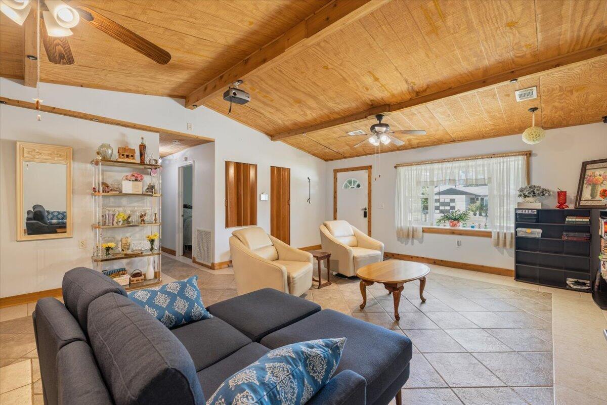 A living room features a vaulted wood-paneled ceiling, tile flooring, and a dark sectional sofa — 1735 40th Avenue, Vero Beach FL 32960, VERO BEACH, FL