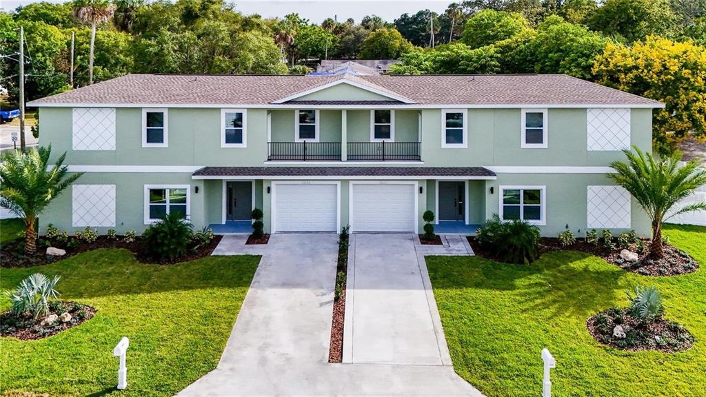 A two-story duplex with a light green exterior, two garages, and a shared upper balcony — 5630 QUEENER AVENUE, PORT RICHEY, FL