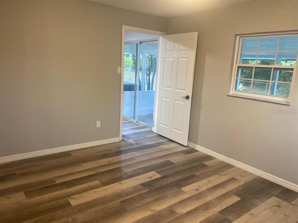 A bedroom with gray walls, wood-look flooring, a white door, and a window — 473 LAKE ROAD, OCALA, FL
