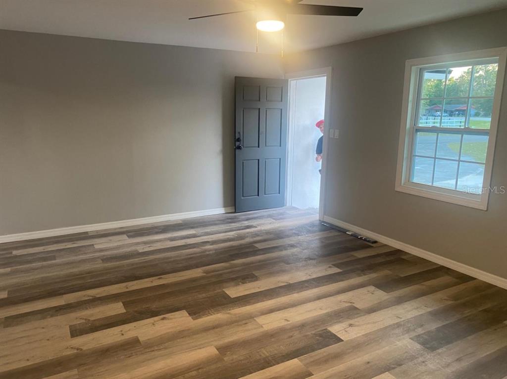 A room with gray walls, wood-look flooring, a ceiling fan, and an open doorway — 473 LAKE ROAD, OCALA, FL