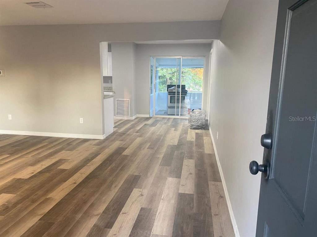 An interior view shows a living area with wood-look flooring leading to a sliding glass door — 473 LAKE ROAD, OCALA, FL